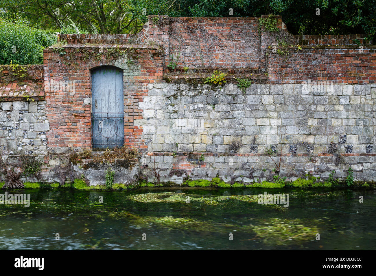 Ancient stone wall and door on a river bank in Winchester, Hampshire
