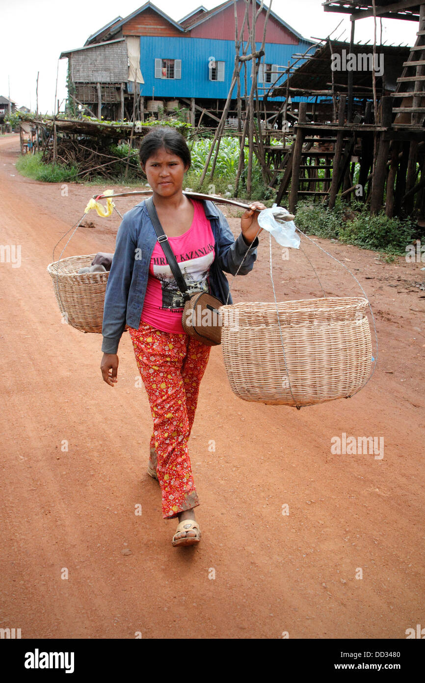 Cambodian lady carrying baskets on dirt road in Kampong Khleang in