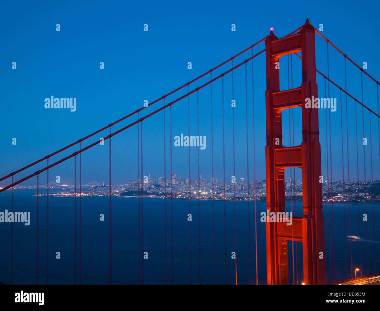 A spectacular view of the Golden Gate Bridge at blue hour, with the illuminated skyline of San Francisco in the background. Stock Photo