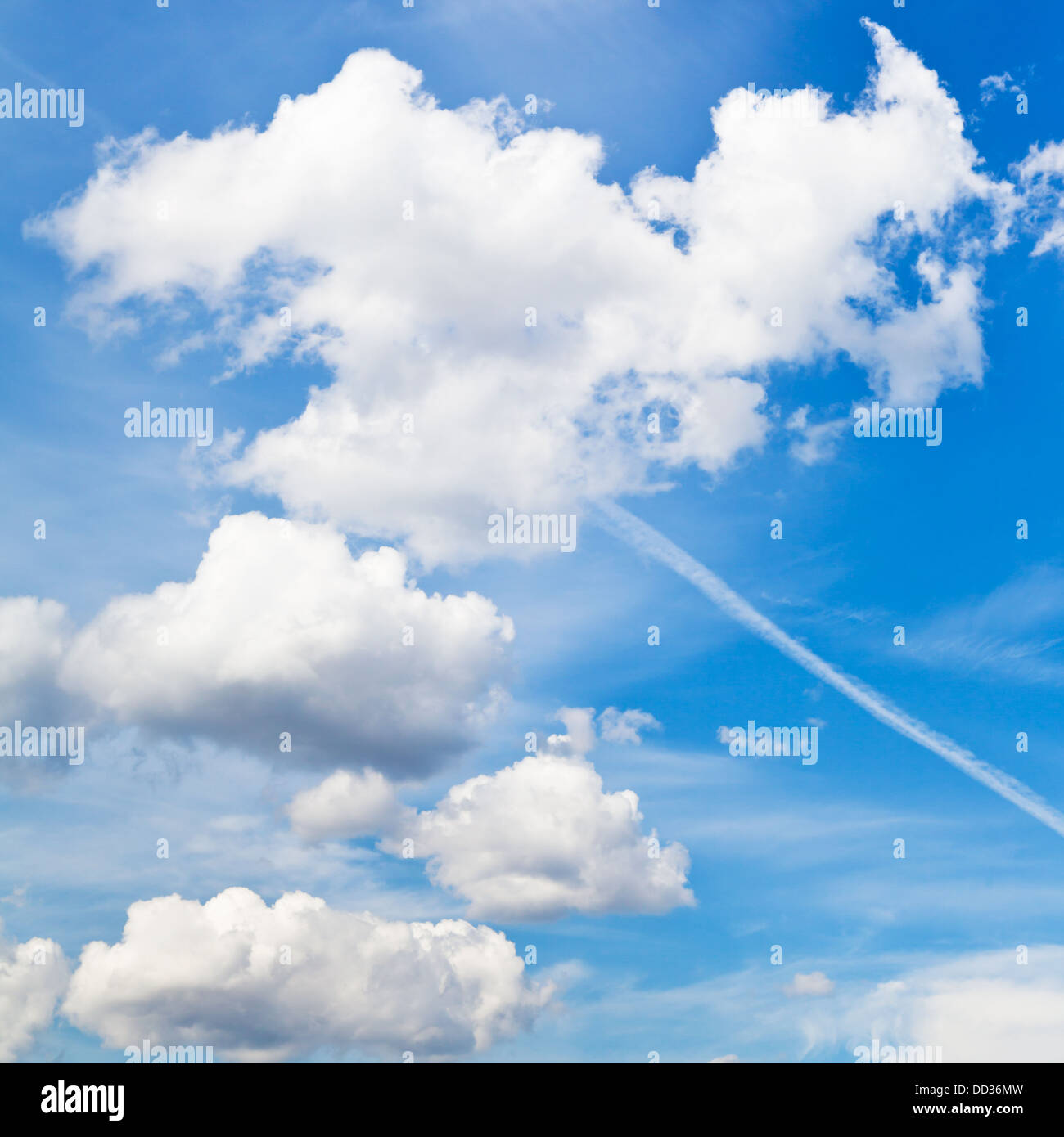 cloudscape with white fluffy clouds and trace of plane in blue sky in summer day Stock Photo
