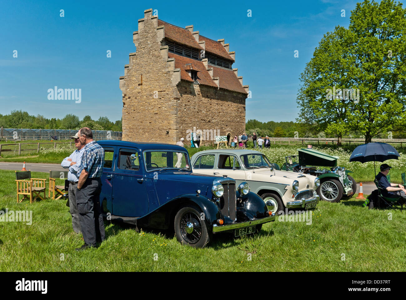 Vintage car rally in the village of Willington, with the National Trust owned Willington Dovecote in the background. Taken from a public highway. Stock Photo