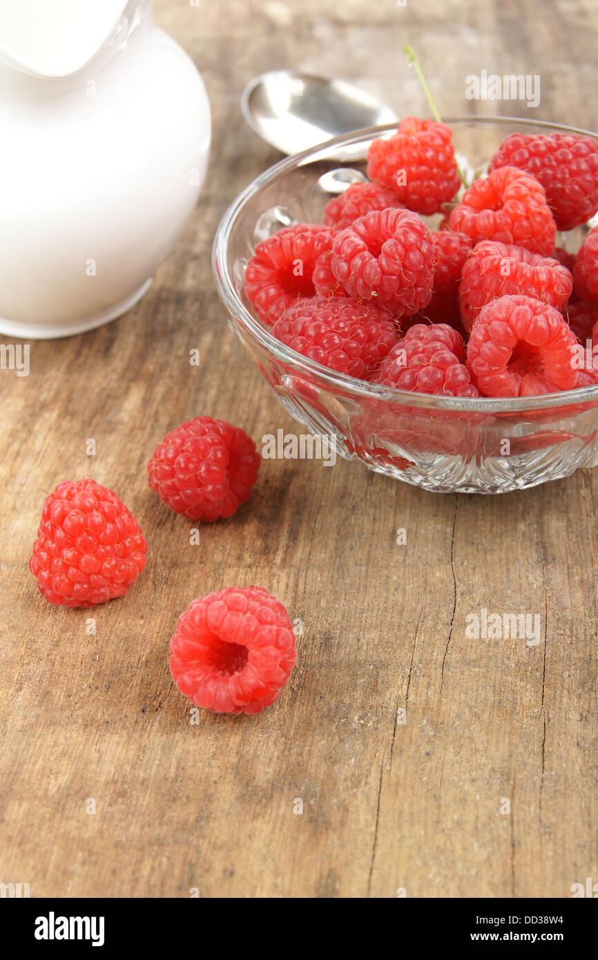 Fresh raspberries just picked in a glass bowl with a jug of fresh cream Stock Photo