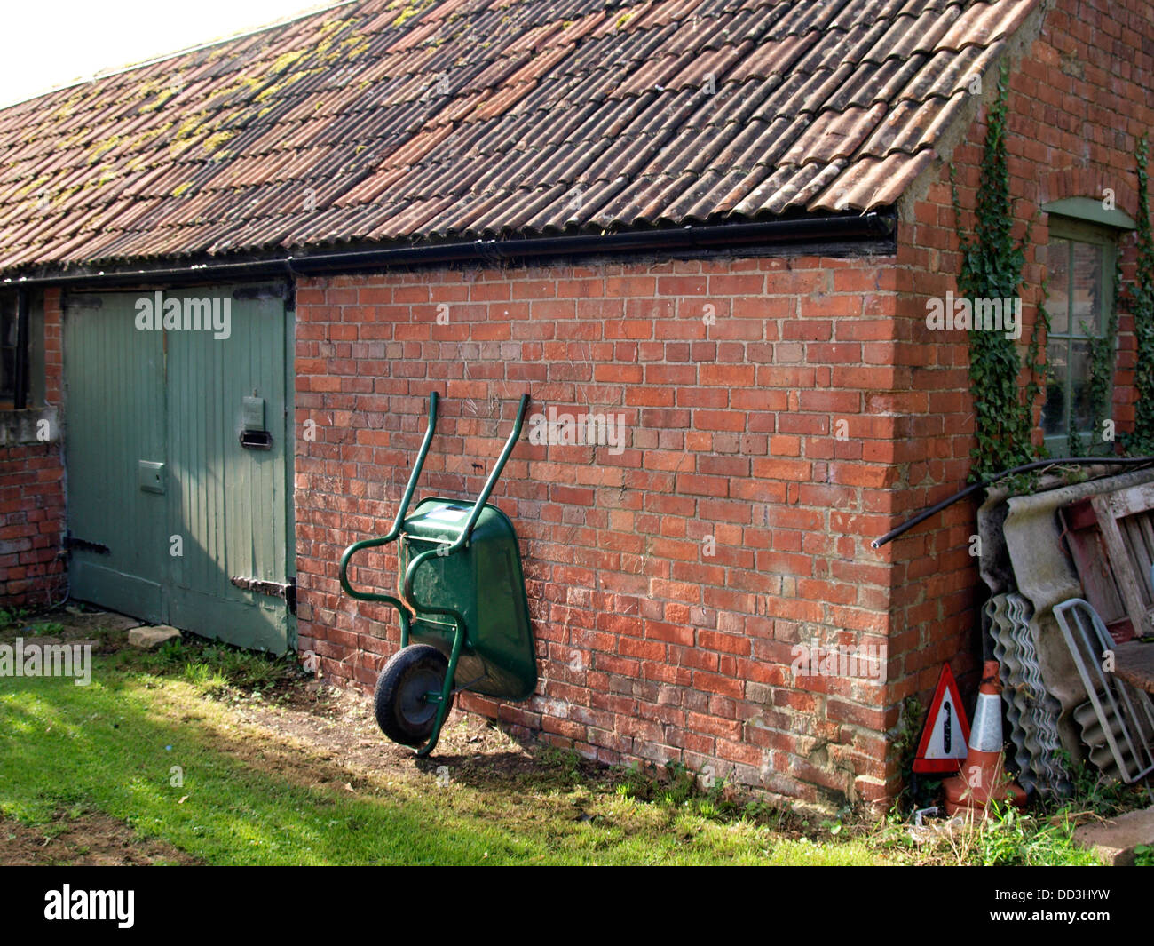 Wheelbarrow lent against the wall of an outbuilding, UK 2013 Stock Photo