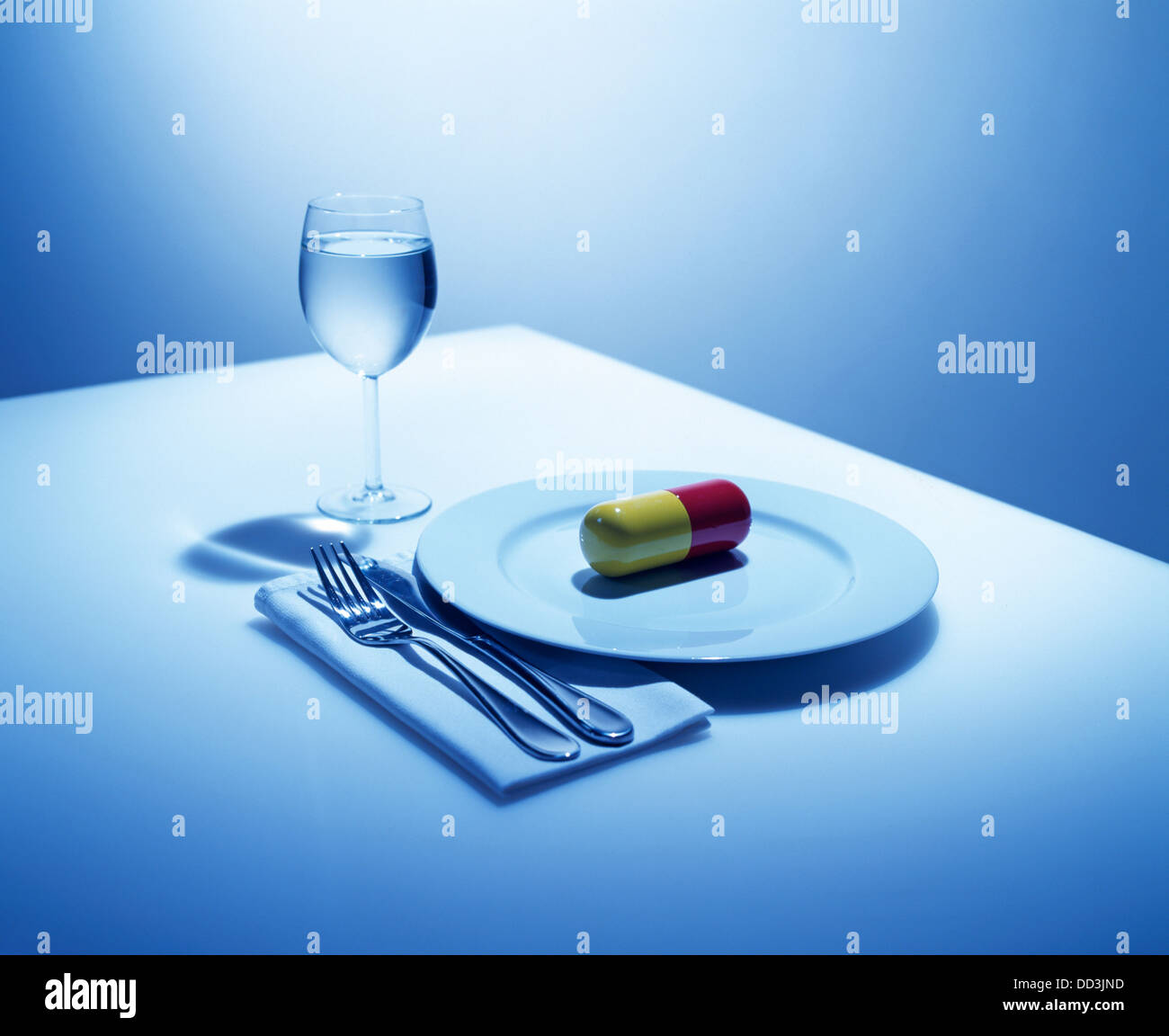 A dinning place setting with just an over sized capsule on the plate. Stock Photo
