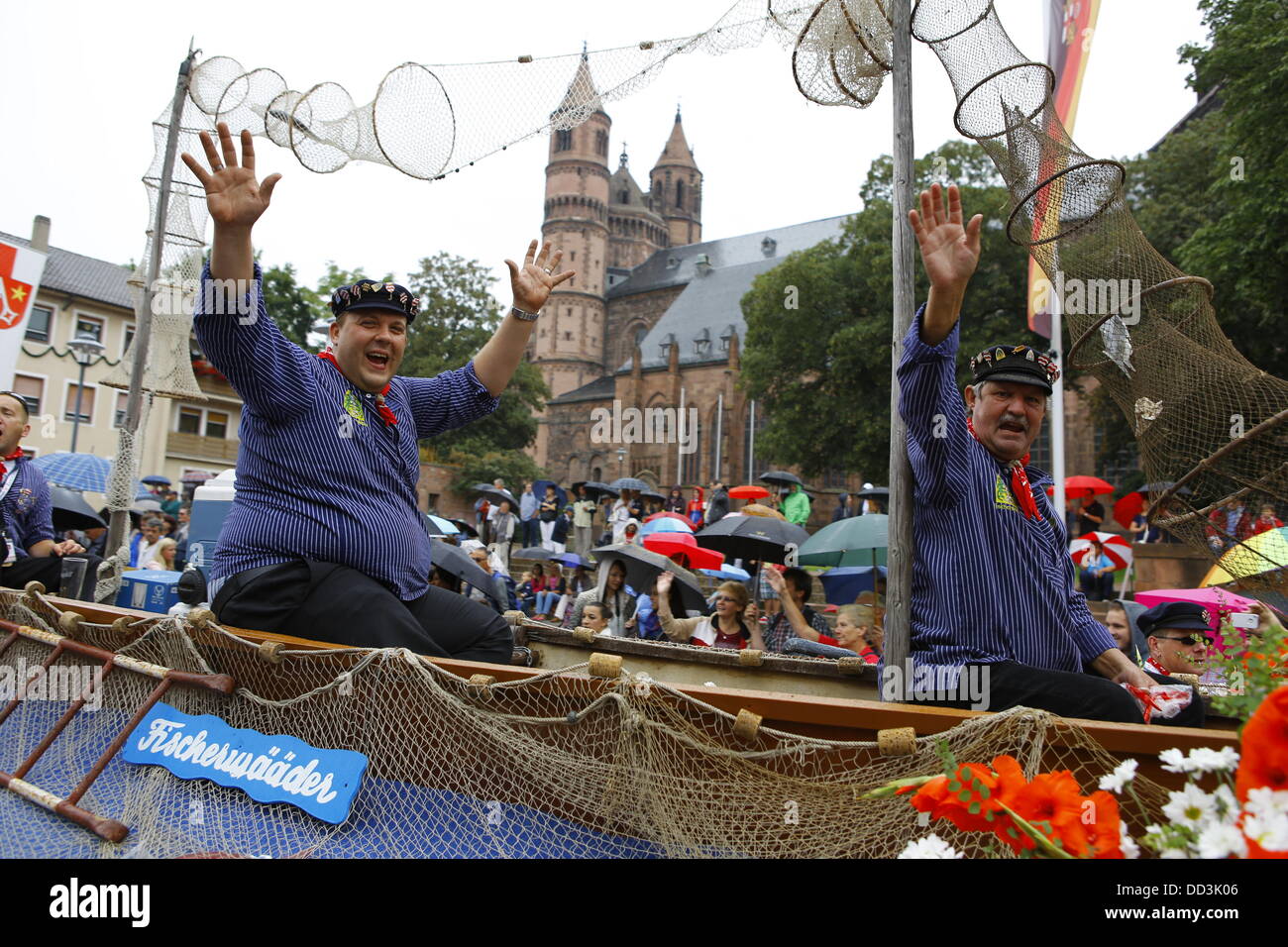 Worms, Germany. 25th August 2013. Members of the fishermen's guild are pictured in a wooden boat at the Backfischfest parade 2011. The cathedral of Worms can be seen in the background. The first highlight of this year's Backfischfest was the big parade through the city of Worms with over 100 groups and floats. Community groups, sport clubs, music groups and business from Worms and further afield took part. Credit:  Michael Debets/Alamy Live News Stock Photo