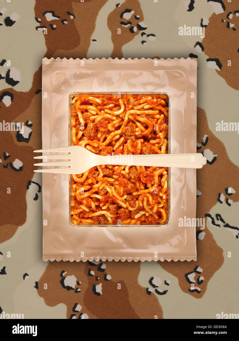 Military food rations or MRE Meals Ready to Eat on a camouflaged background. Packages open with plastic utensils. Stock Photo