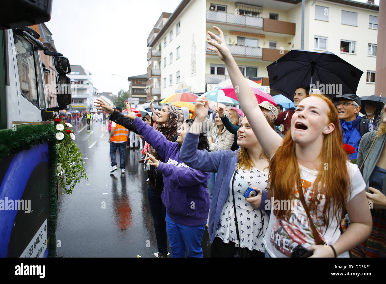 Worms, Germany. 25th August 2013. Members in the crowd stretch their arms in the air, to catch the sweets thrown into the crowd from the floats. The first highlight of this year's Backfischfest was the big parade through the city of Worms with over 100 groups and floats. Community groups, sport clubs, music groups and business from Worms and further afield took part. Credit:  Michael Debets/Alamy Live News Stock Photo