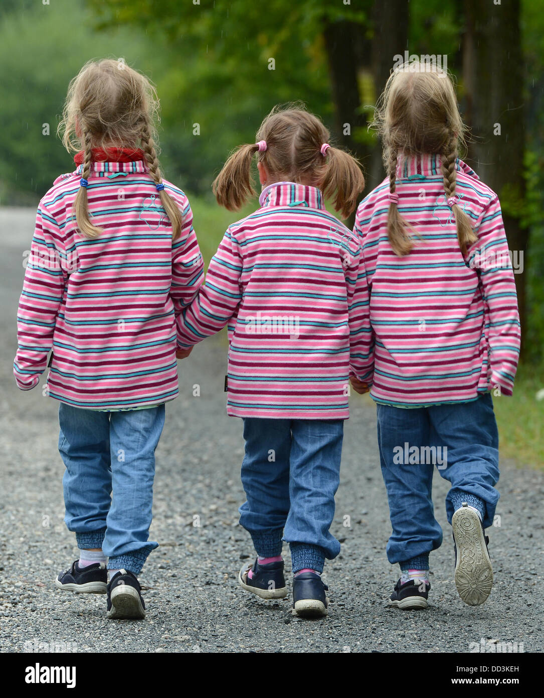 The triplets Leni (L-R, 5), Emely and Nele walk along a street at the Triplet meeting held at Hessen Park on a rainy day in Neu-Anspach, Germany, 25 August 2013. The governor of Hesse is a godfather for all children of multiple births and hosts an event each year for them. Photo: ARNE DEDERT Stock Photo