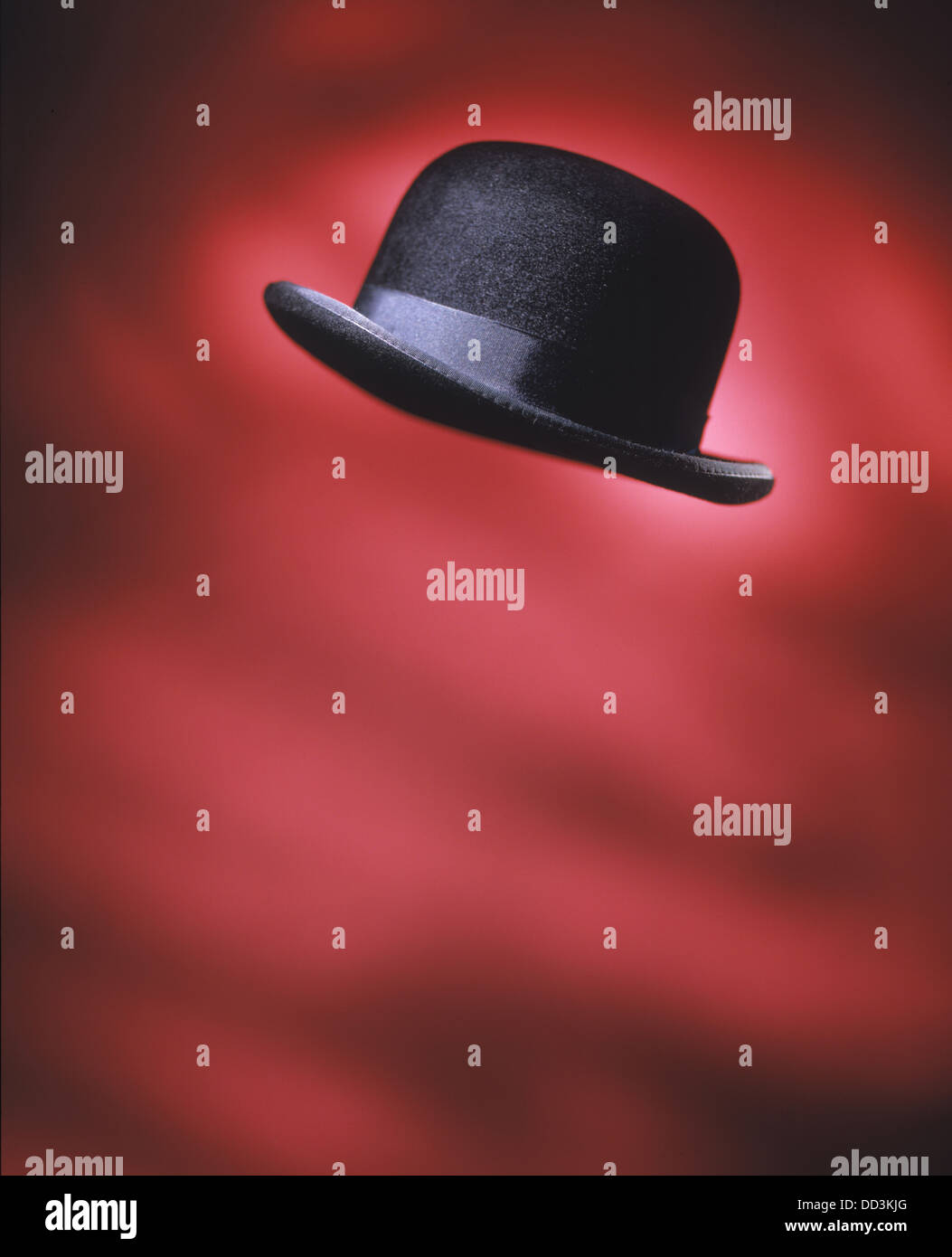 A black mens derby hat flying in the air. Bright red background Stock Photo