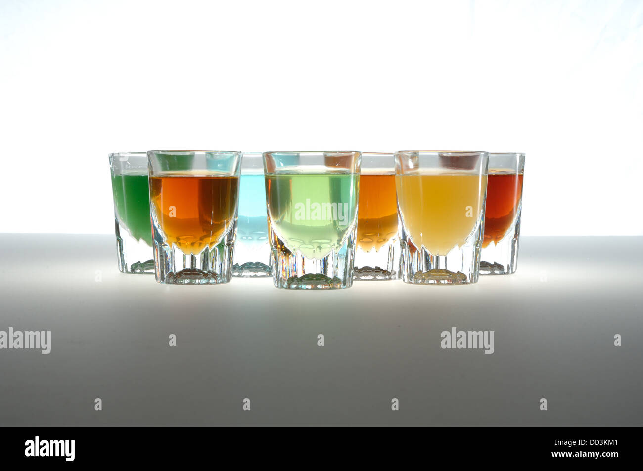 Small barware glasses filled with colorful liquids. Also known as shot glasses. Stock Photo