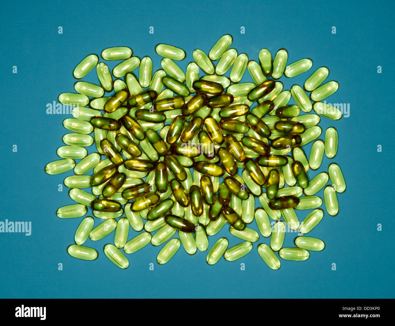 A large group of green capsule pills on a blue background Stock Photo