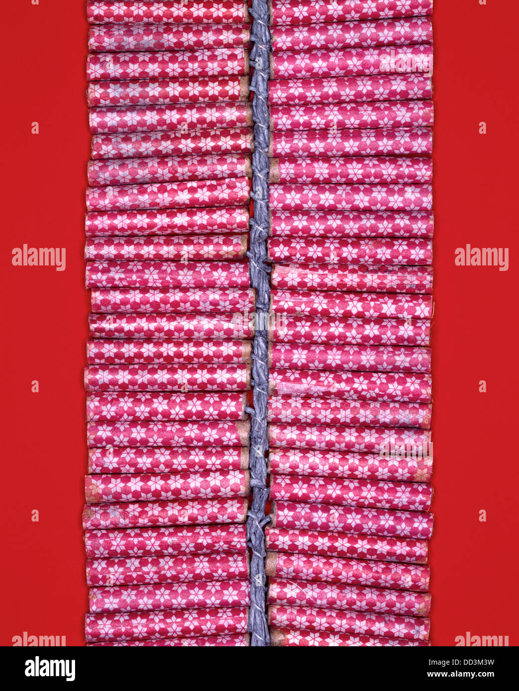 A string of red firecrackers held by a fuse. Bright red background Stock Photo