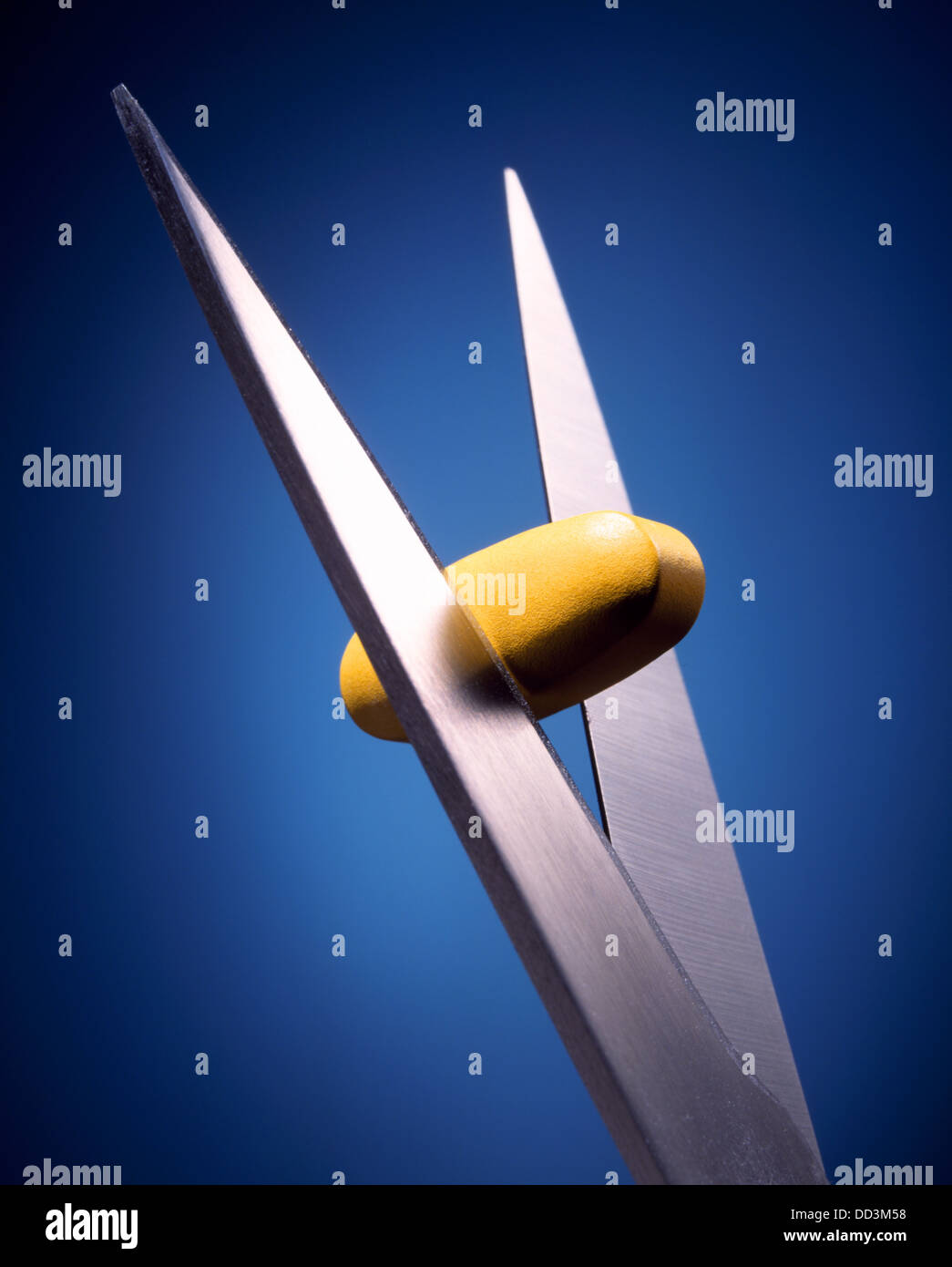 A large yellow medicine pill being cut in half with large metal