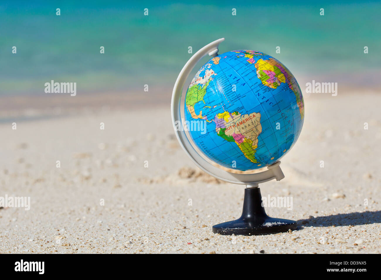 Globe on caribbean beach, travel concept  Stock Photo