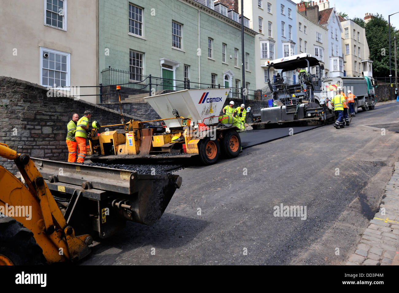 Road repair. Asphalt and chippings being spread while resurfacing street Stock Photo