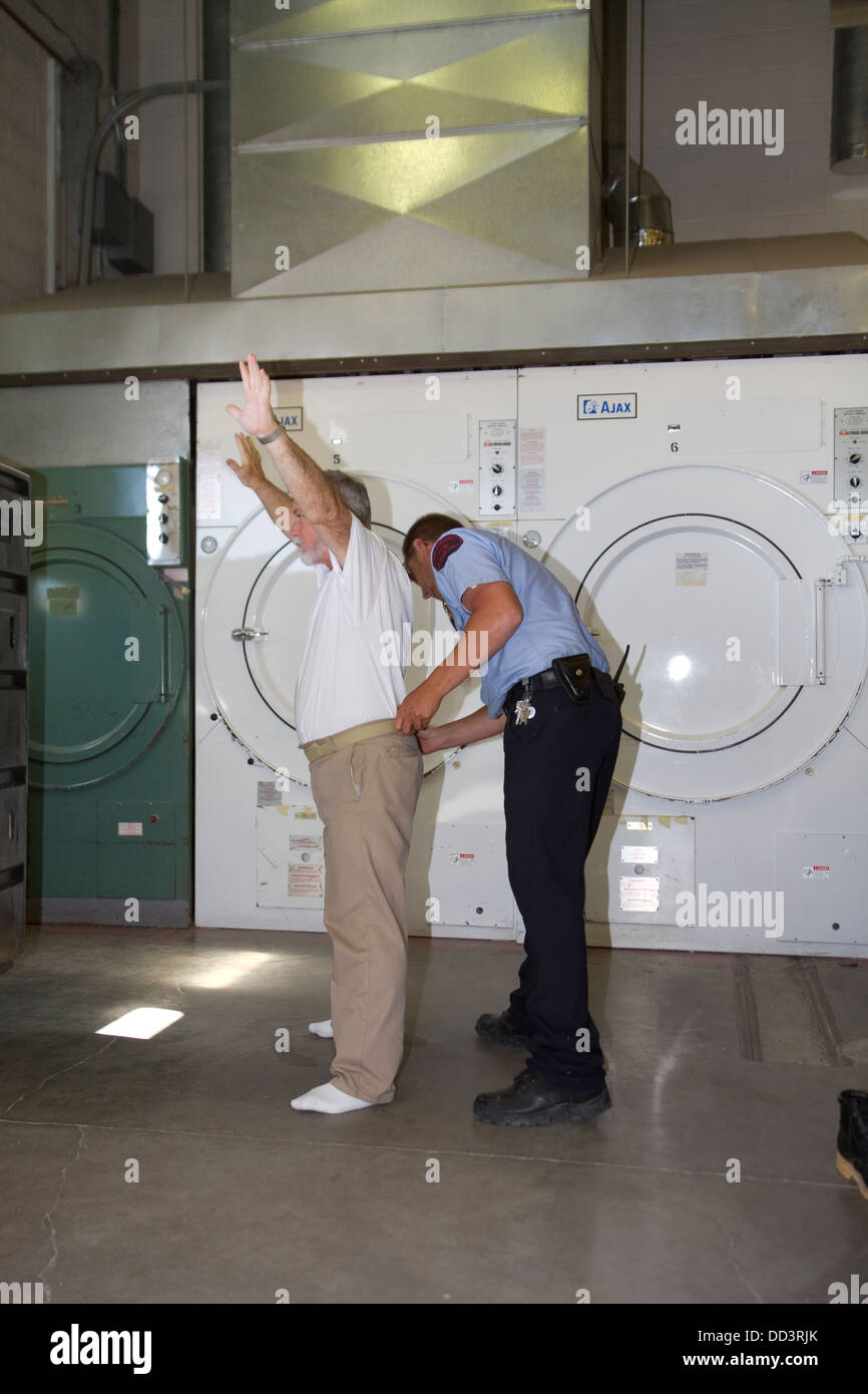 Sergeant pat searching inmate working in laundry. American maximum security prison. Stock Photo