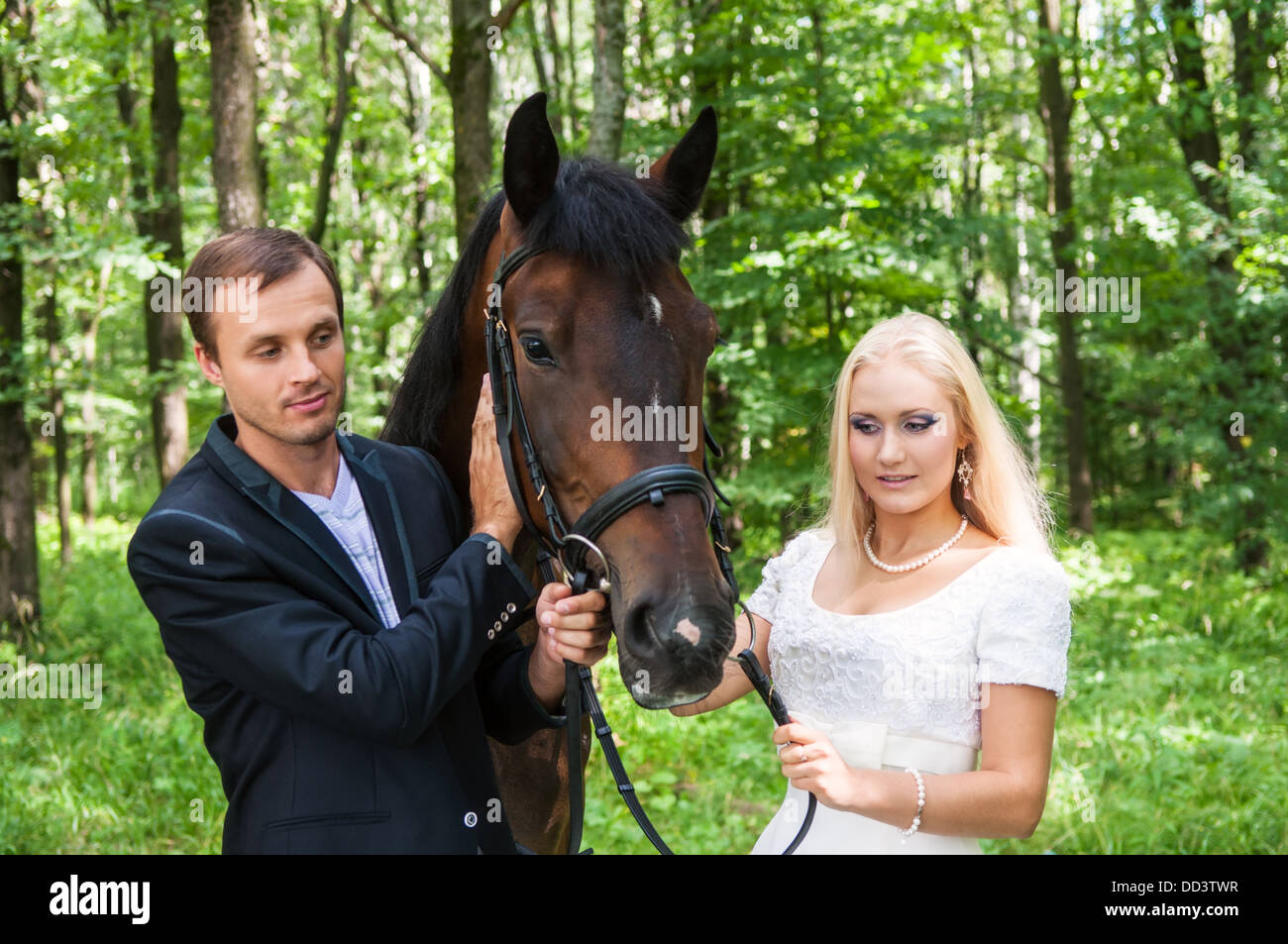 Beautiful bride and groom with a horse in the forest Stock Photo - Alamy