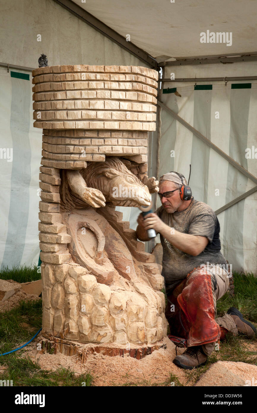 Tabley, Cheshire, UK 25th August, 2013. Steven Kenzora from Canada at the 9th English Open Chainsaw Carving Competition,  Cheshire County Showground, Game and County Fair, The chainsaw carvers use wood (sometimes huge bits) to produce beautiful carvings of up to 20 feet high. when each one becomes a sought after work of art.  Wood sculpture, sawdust, sculptor, timber, chips, log, professional, working, art, artist, cut, chain saw, artwork made from rough timber log. Stock Photo