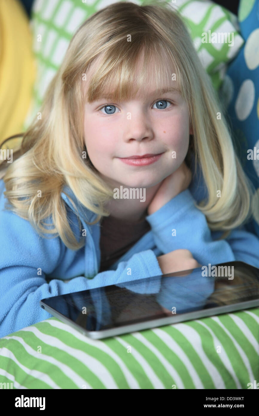 Girl Laying On A Couch Playing With A Tablet; Troutdale, Oregon, United States of America Stock Photo