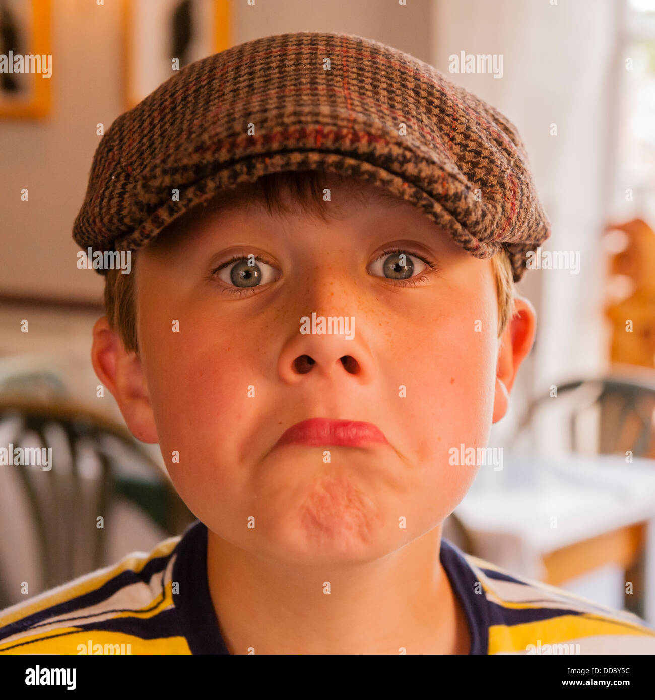 A 9 year old boy wearing a cap and pulling a funny face in the Uk Stock Photo