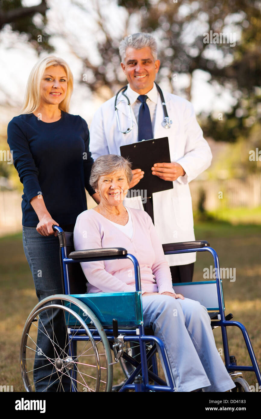 happy disabled senior woman on wheelchair and daughter meeting retirement village doctor outdoors Stock Photo