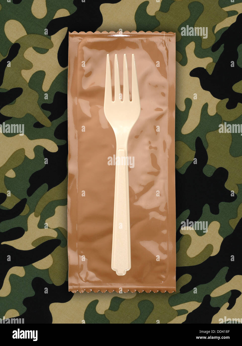Military food rations or MRE Meals Ready to Eat on a camouflaged background. Packages open with plastic utensils. Stock Photo