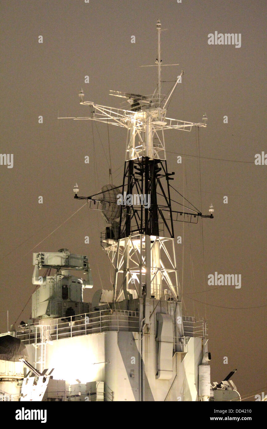 Mast of HMS Belfast at night floodlit on the River Thames in winter Stock Photo