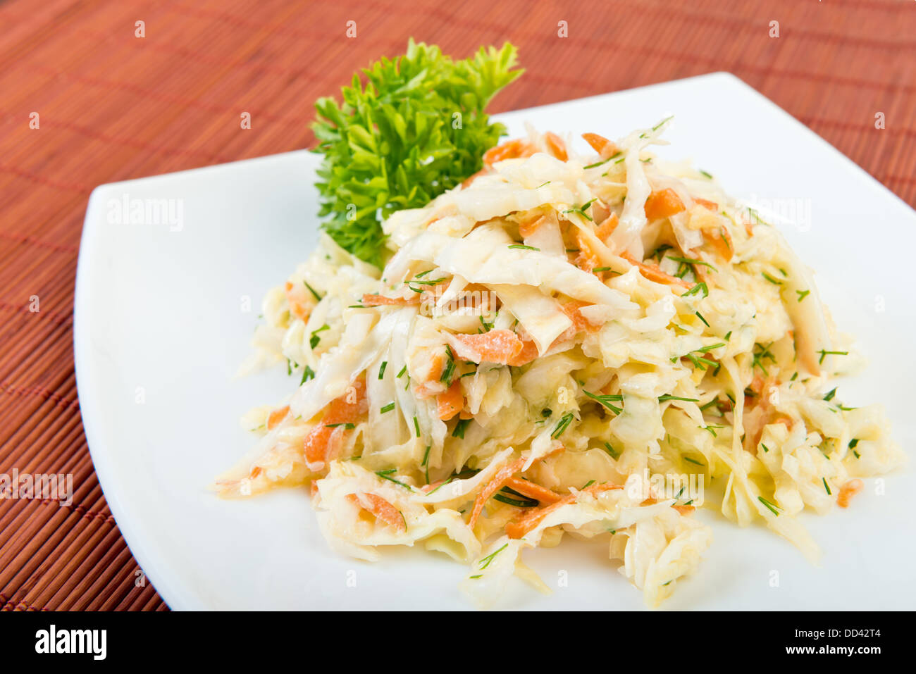 Low fat vegetable salad coleslaw (cabbage, carrot, dill, mayonnaise) on plate at restaurant table Stock Photo