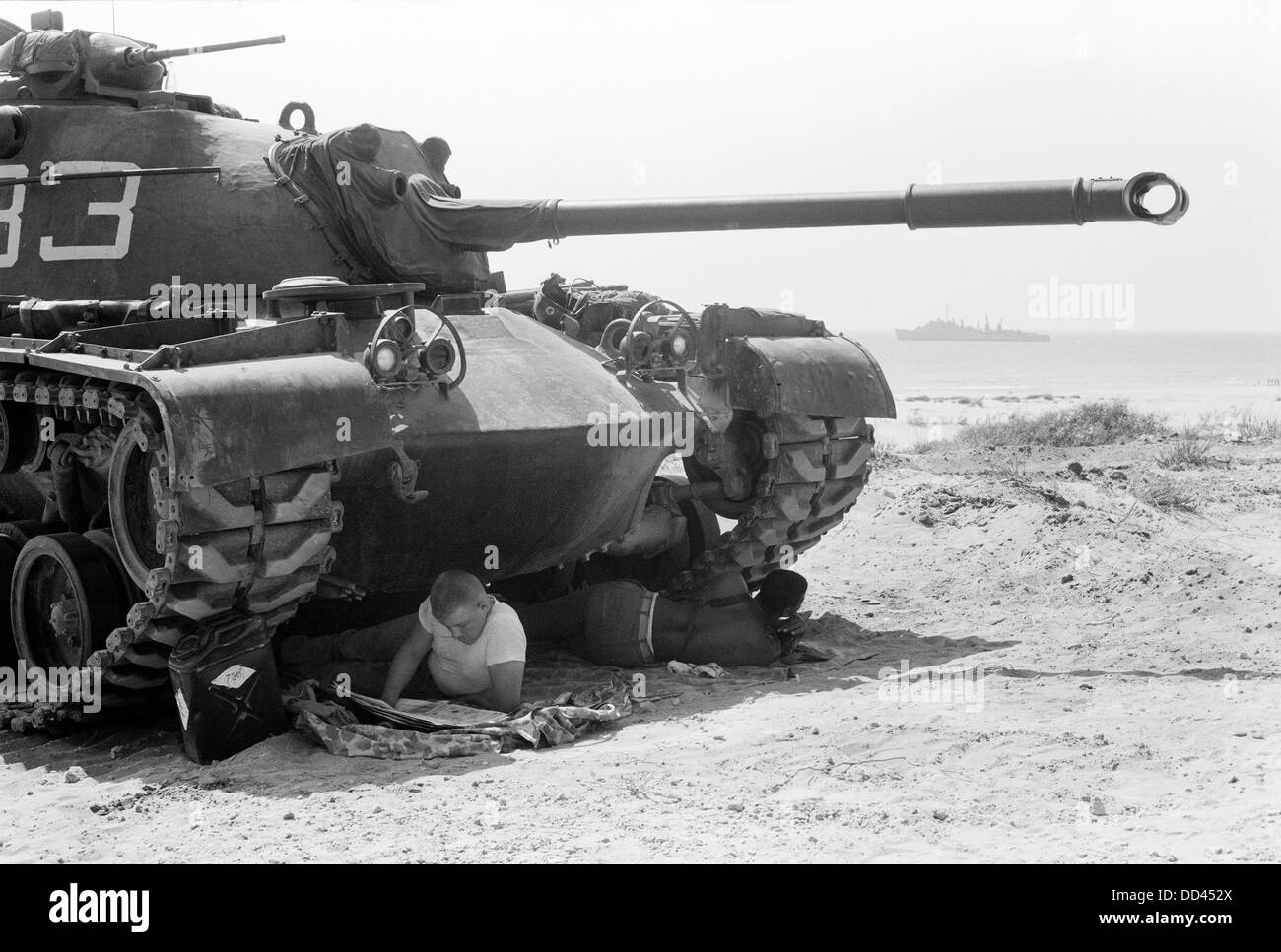 American soldier reads a newspaper in the shade under a U.S. Marine tank in Beirut, Lebanon Stock Photo