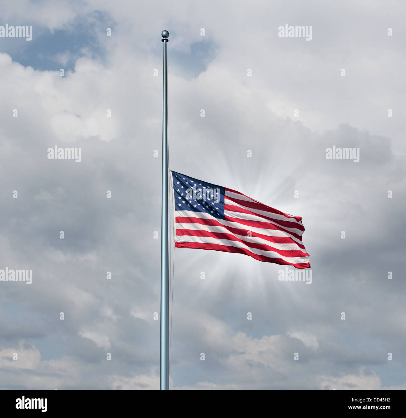 Half mast American flag concept with the symbol of the United States flying at low level on the flagpole or staff on a cloudy day with a sun glow as an icon of honor respect and mourning for fallen heros. Stock Photo