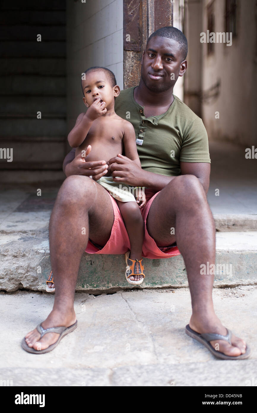 A Cuban man with his child on his knees in the street in Havana, capitol city of Cuba Stock Photo