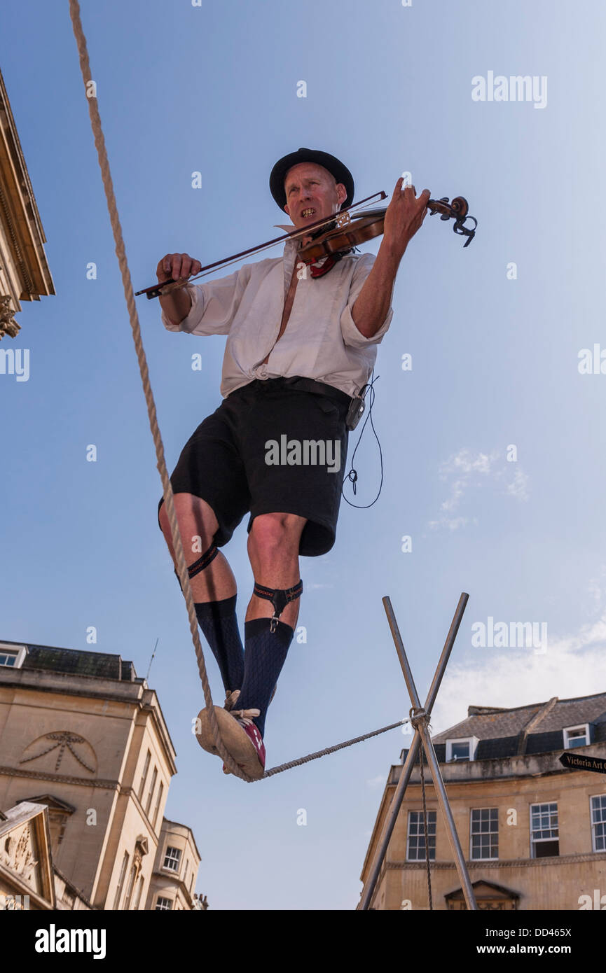 A tightrope walker busking playing a violin in Bath , Somerset , England , Britain , Uk Stock Photo
