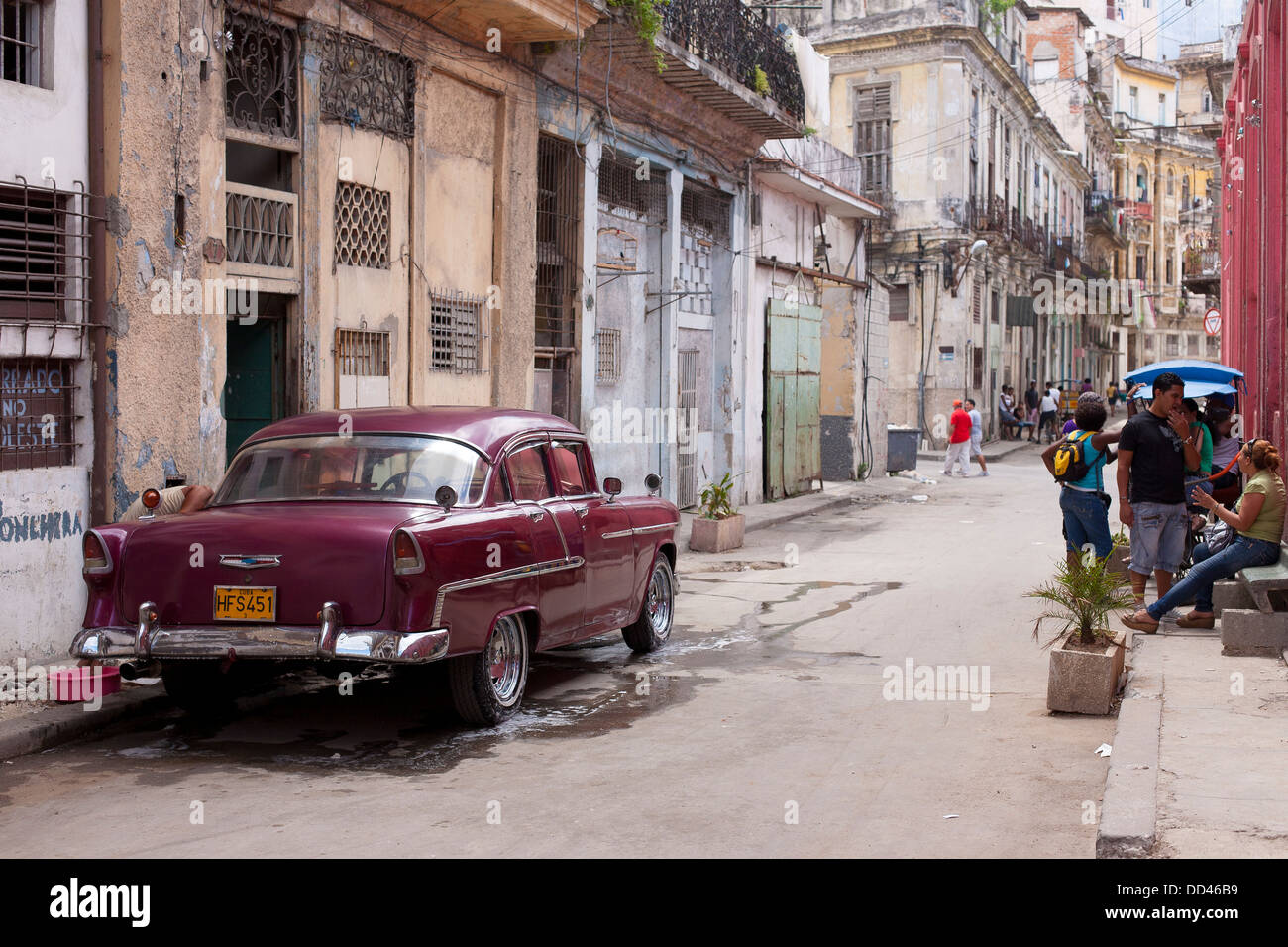 A classic American automobile being washed on the street in Havana