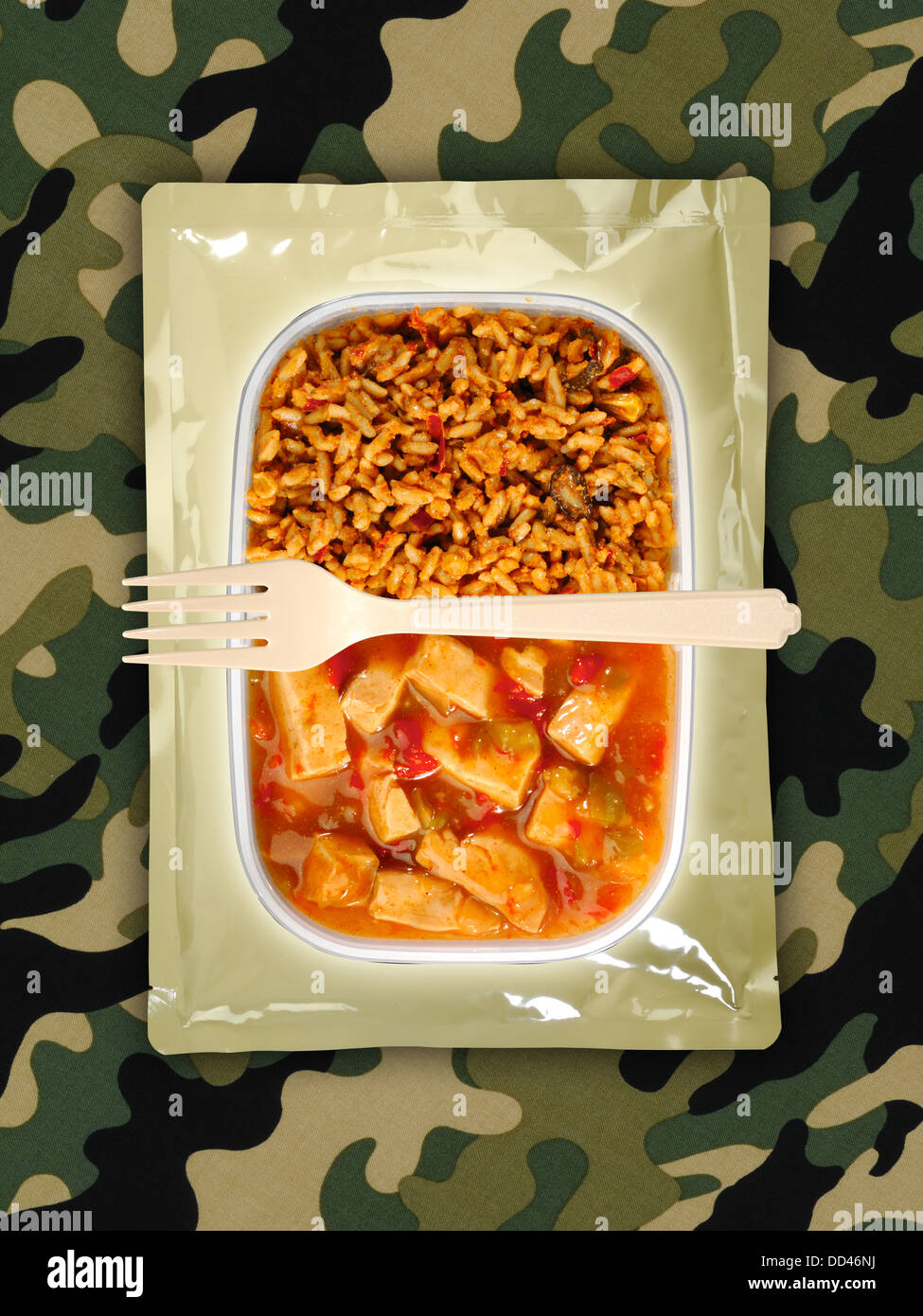 Military food rations or MRE Meals Ready to Eat on a camouflaged background. Packages open with plastic utensils. Stock Photo