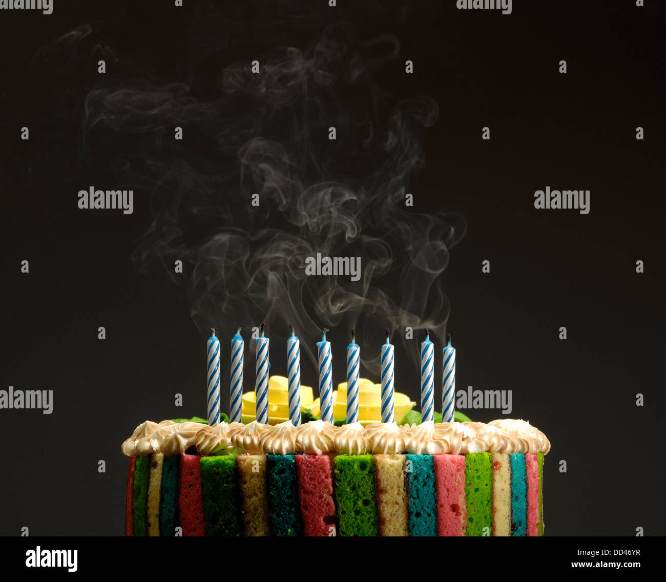 A colorful birthday cake with blown out candles and smoke Stock Photo