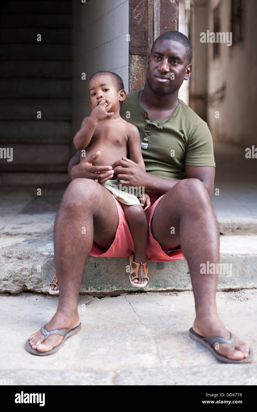 A Cuban man with his child on his knees in the street in Havana, capitol city of Cuba Stock Photo