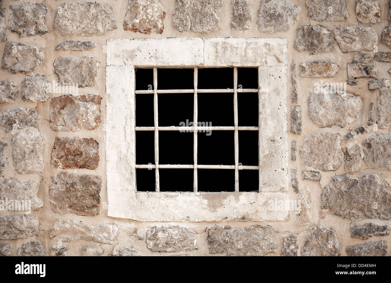 Ancient stone prison wall with metal window bars Stock Photo