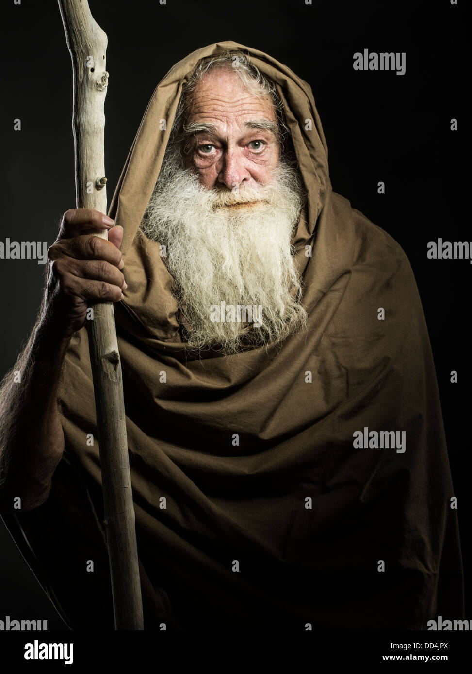 old man with white beard staff and cloak looks like wizard / Gandalf