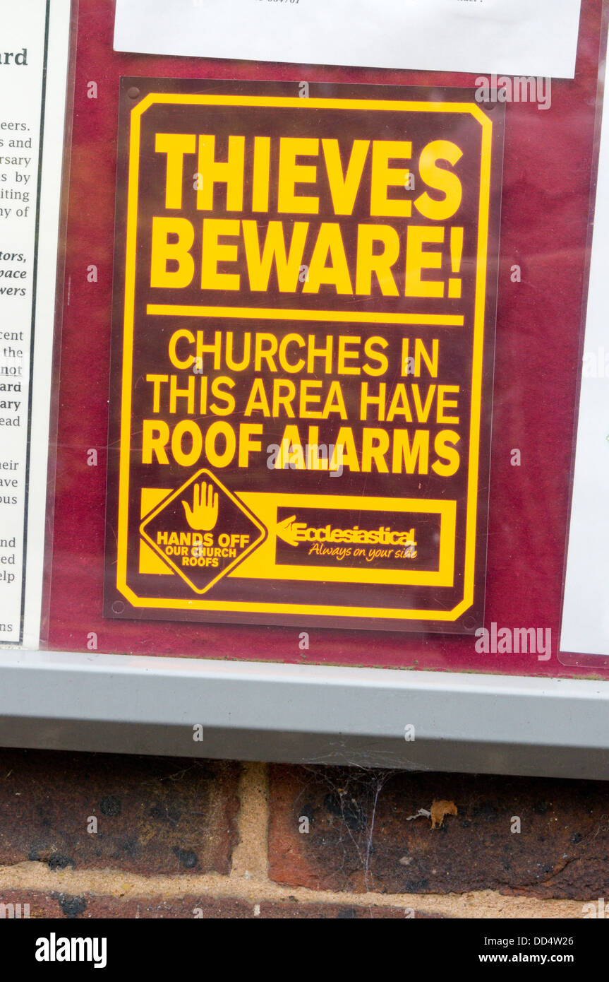 Sign warning potential thieves that the church roof is fitted with an alarm. Stock Photo