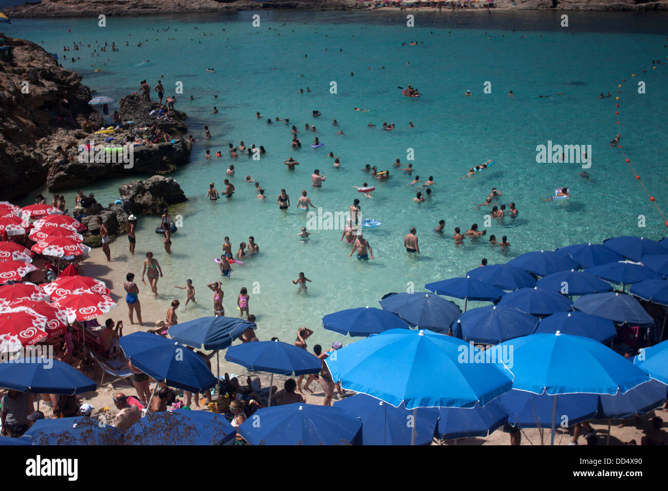 Blue sun umbrellas decorate Comino Island as people bathe on the beach, Malta, August 16, 2012. Stock Photo