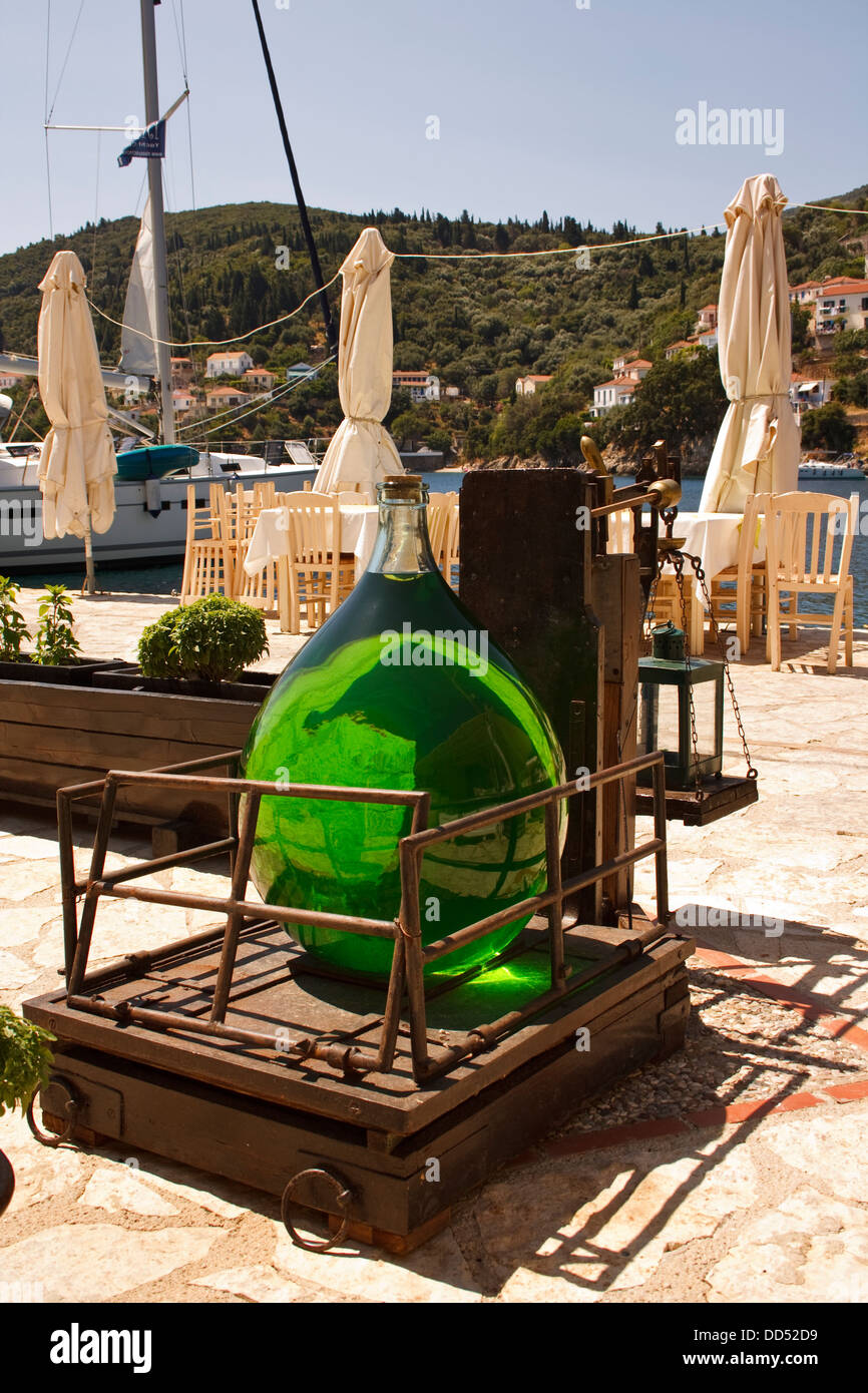 Demijohn of coloured liquid sits on old wooden scales on the quayside at Kioni, on the Greek
