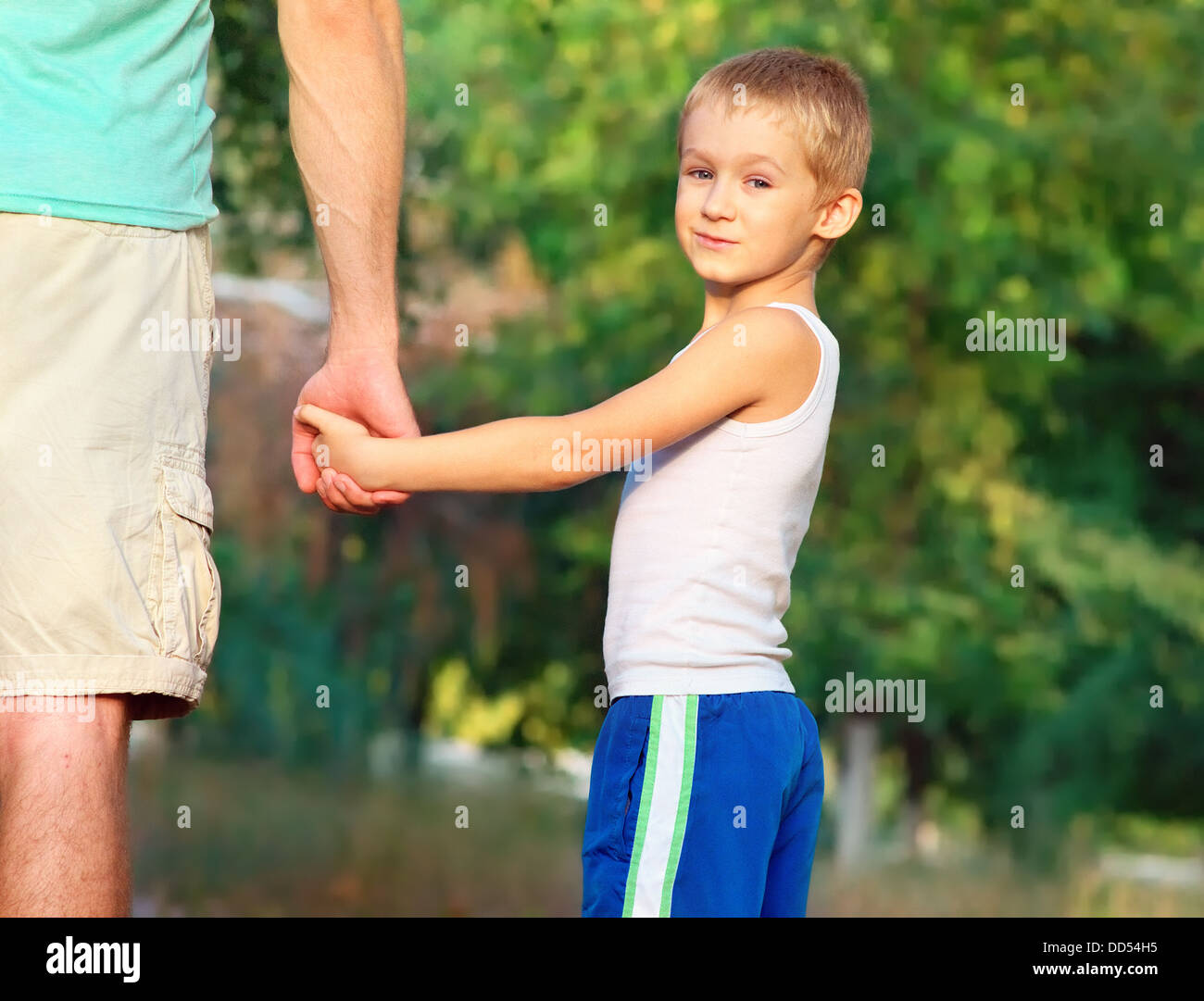 Family Father Man and Son Boy Child holding hand in hand Outdoor Happiness emotion with summer nature on background Stock Photo
