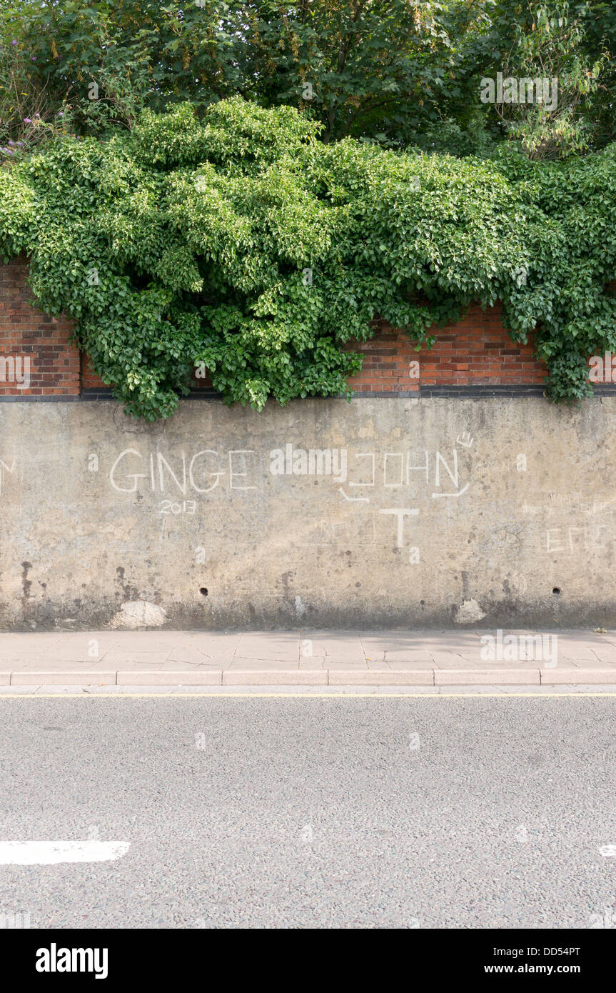 Graffiti scratched into concrete render wall Stock Photo