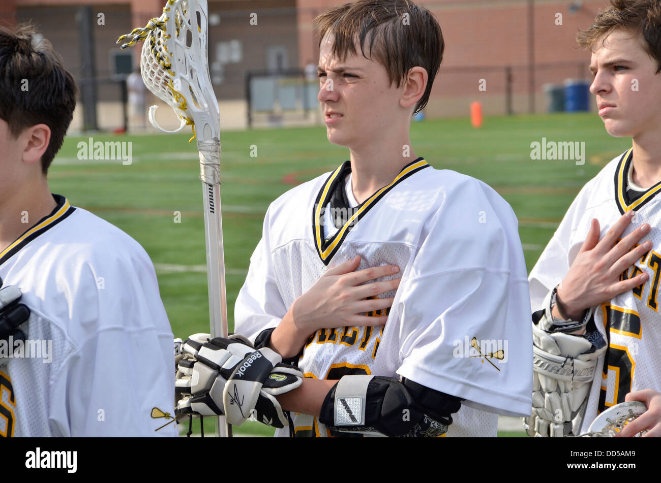 High school lacrosse players stand at attention for the national anthem