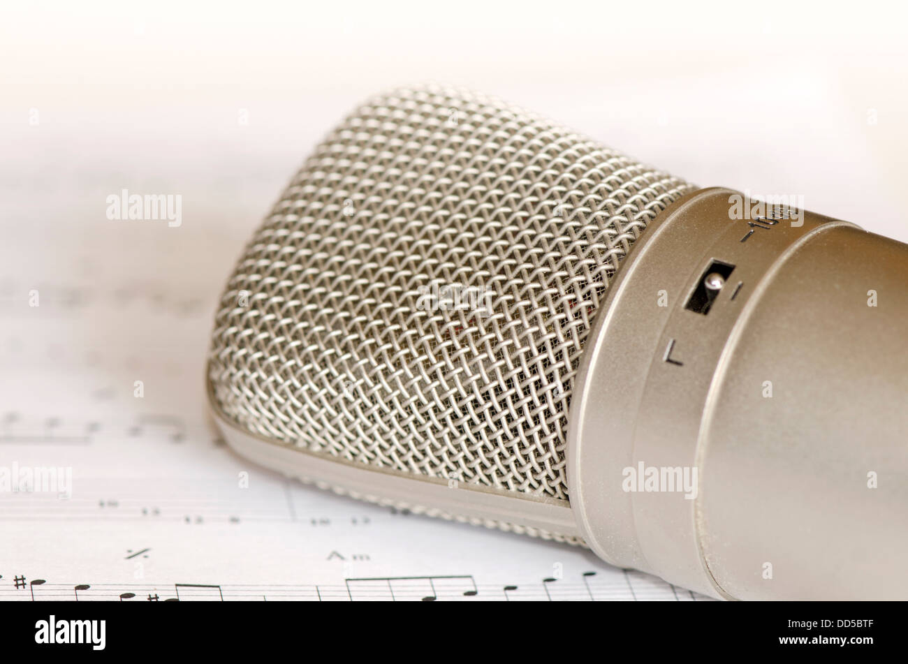 Close-up of a condenser microphone lying on a music book. Stock Photo