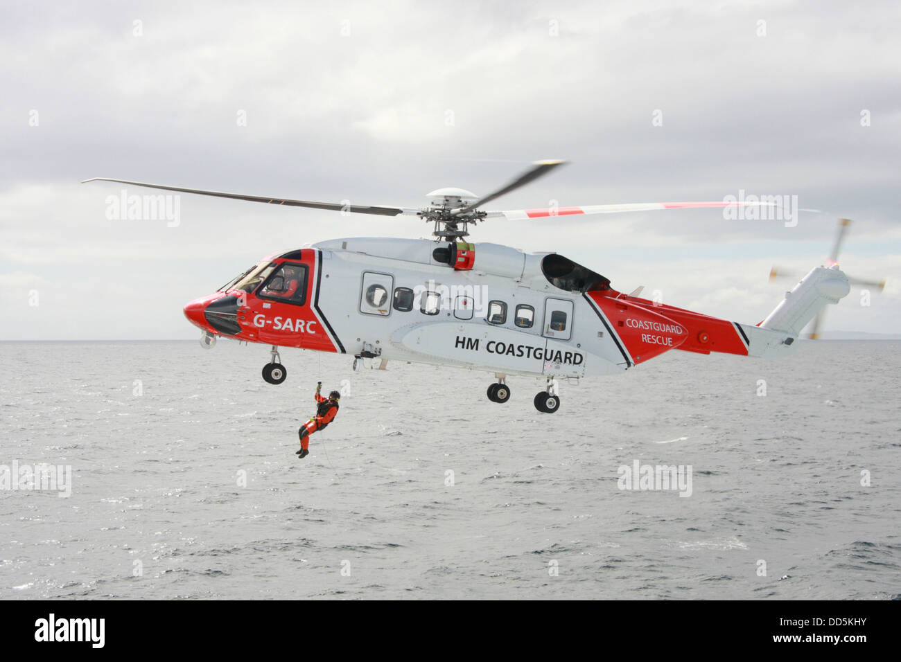 Coastguard search and rescue helicopter on exercise winching a crewman onto a ferry in the Minch near the Outer Hebrides Stock Photo