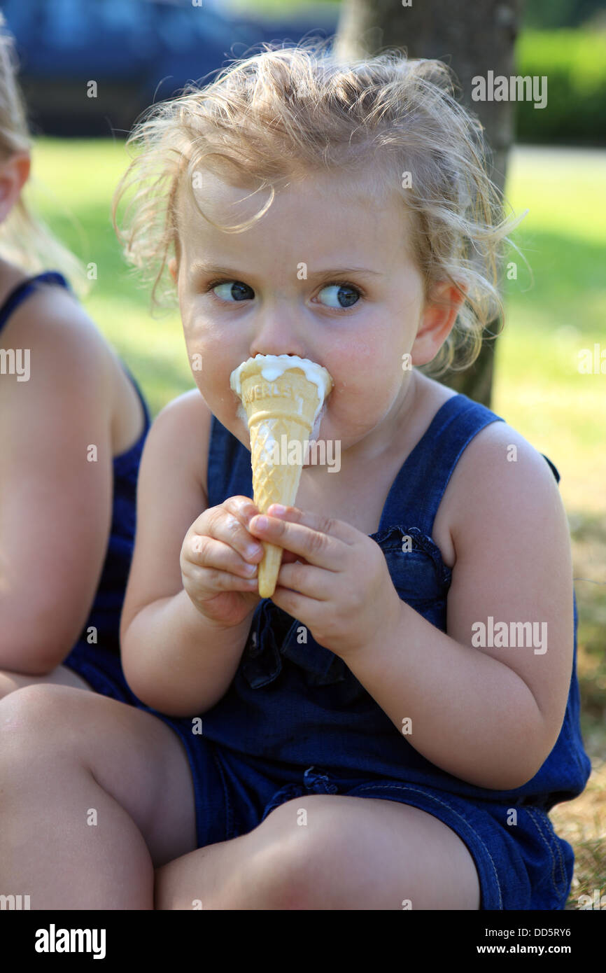 Two year old girl eating an ice cream cone on a hot day Stock Photo