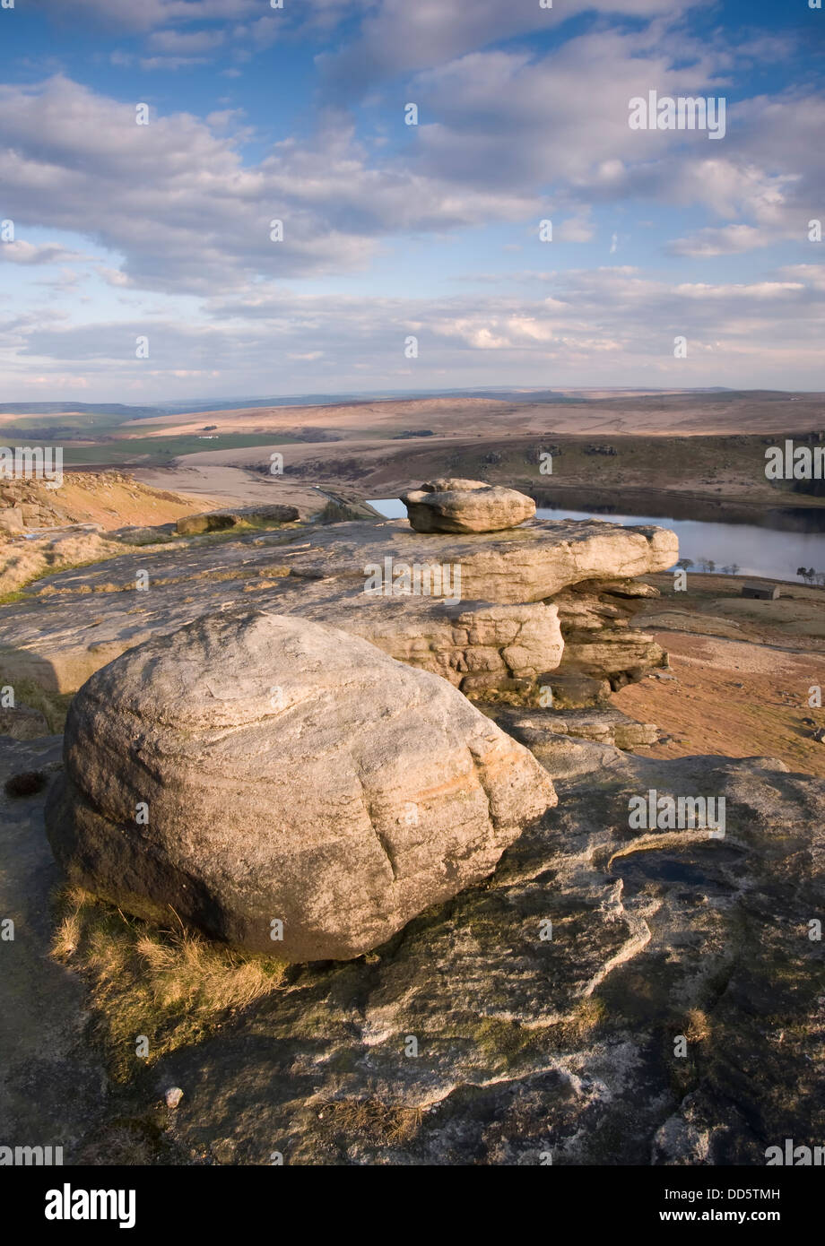 Millstone grit wind shaped boulders on a ridge above a Yorkshire reservoir Stock Photo