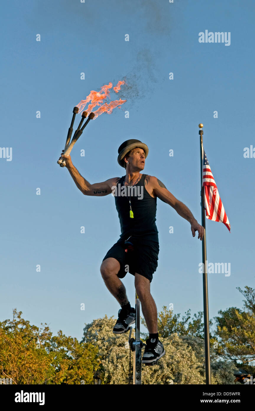 USA, Florida, Key West, Mallory Square, Fire Juggler on a giraffe unicycle prepares to juggle flaming torches at a performance. Stock Photo