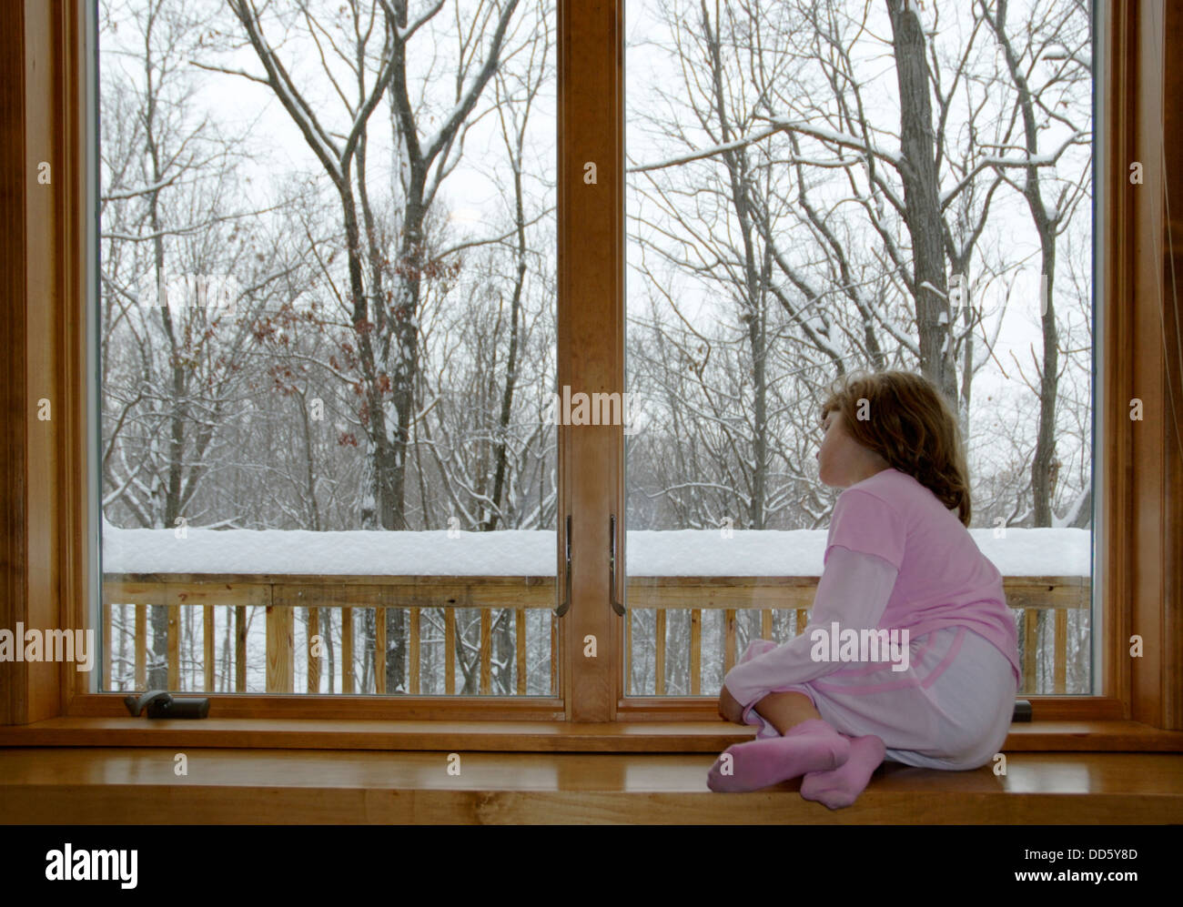 Sad girl winter day looking out window Stock Photo